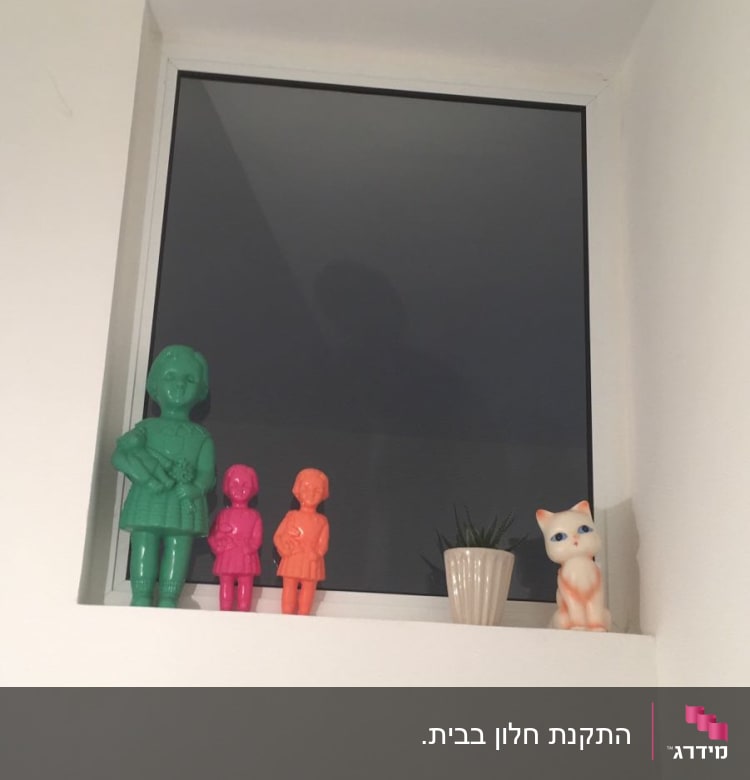 חלון אלומיניום עם פסלונים צבעוניים על אדן החלון